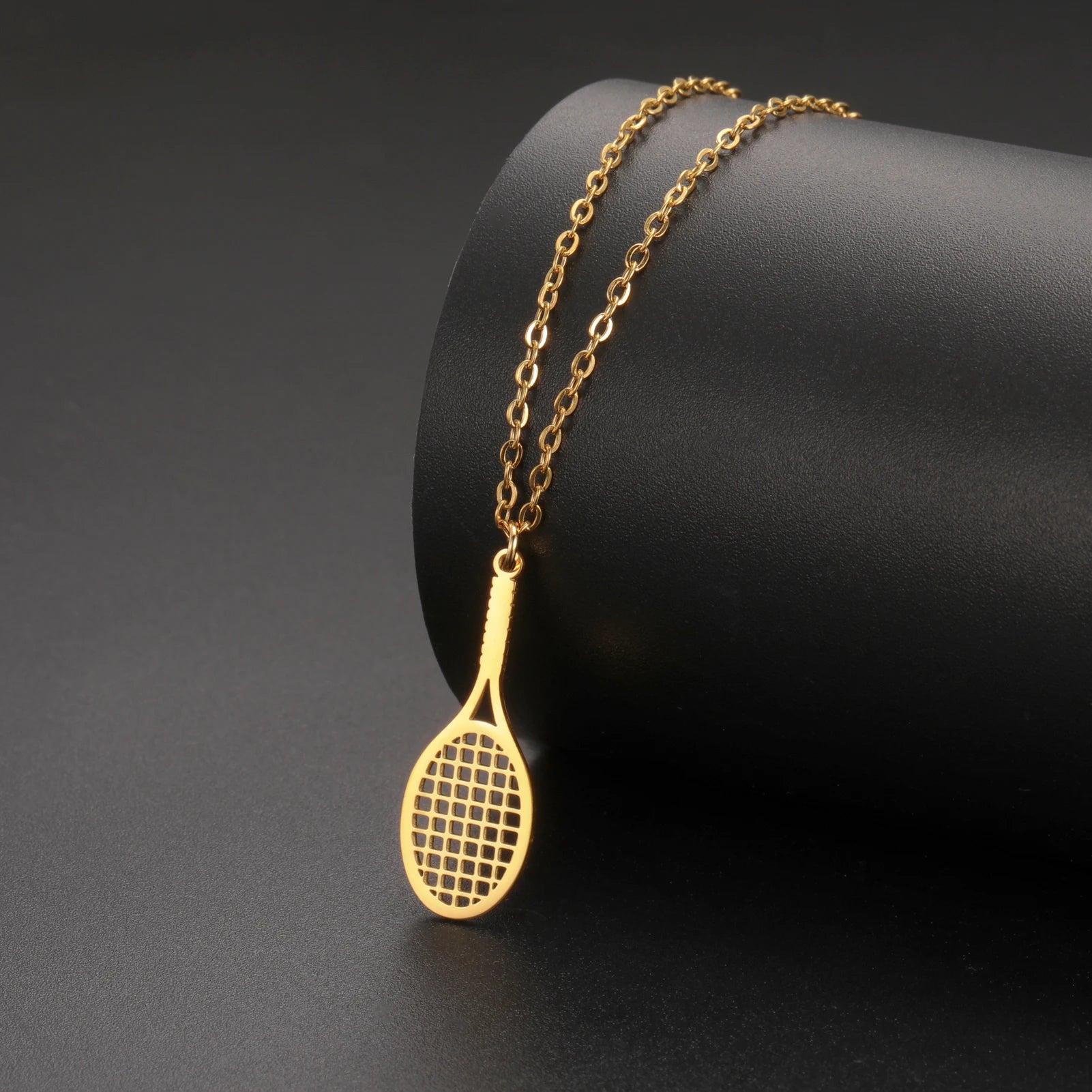 Editorial studio image of premium tennis racket pendant necklace featuring delicate minimalist jewelry design
