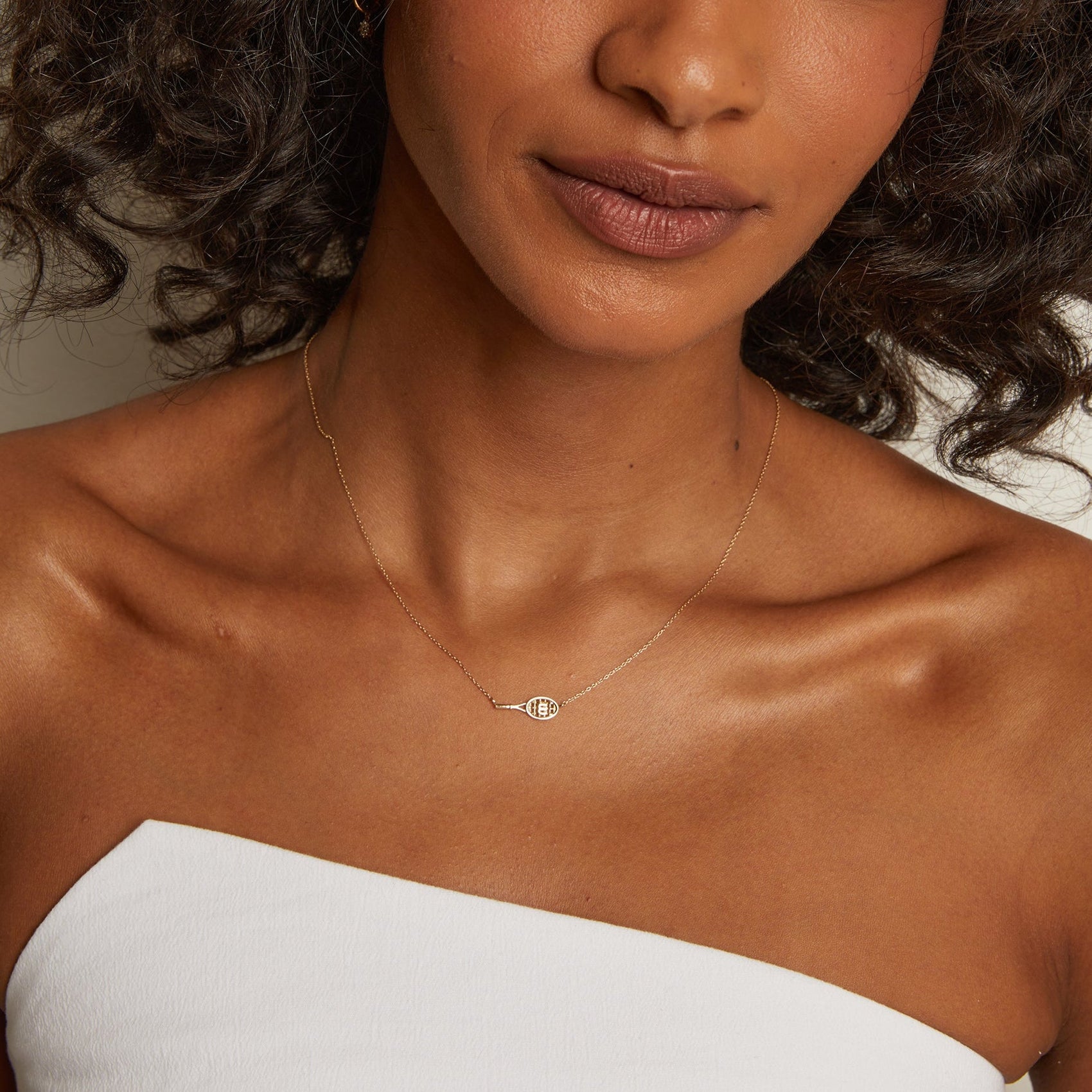 Close-up detail of premium racket pendant necklace with polished finish and understated tennis-inspired elegance