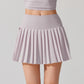 Tennis player in elegant athletic wear showcasing a pleated tennis skirt during court training