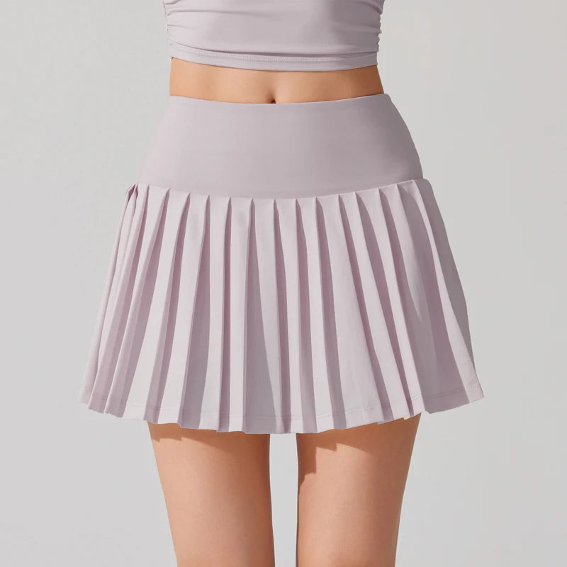 Tennis player in elegant athletic wear showcasing a pleated tennis skirt during court training
