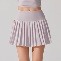Tennis player in elegant athletic wear showcasing a pleated tennis skirt during court training